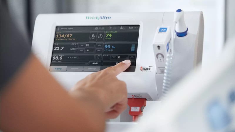 Nurse presses the save button on the Connex Spot Monitor to automatically send patient information to the EMR