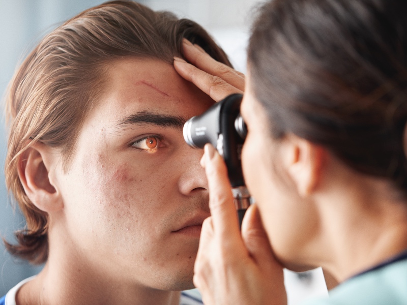 Doctor looking into patients eyes with device.