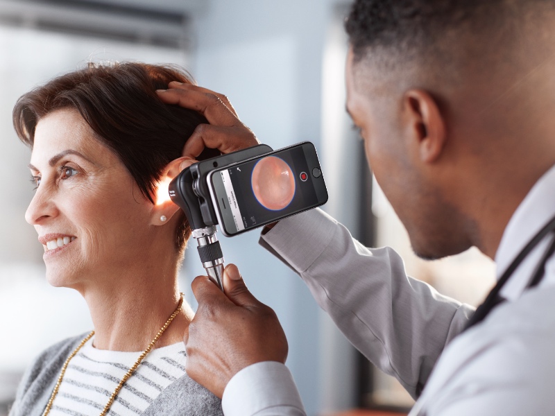 A doctor checking a paitents ear with the otoscope.