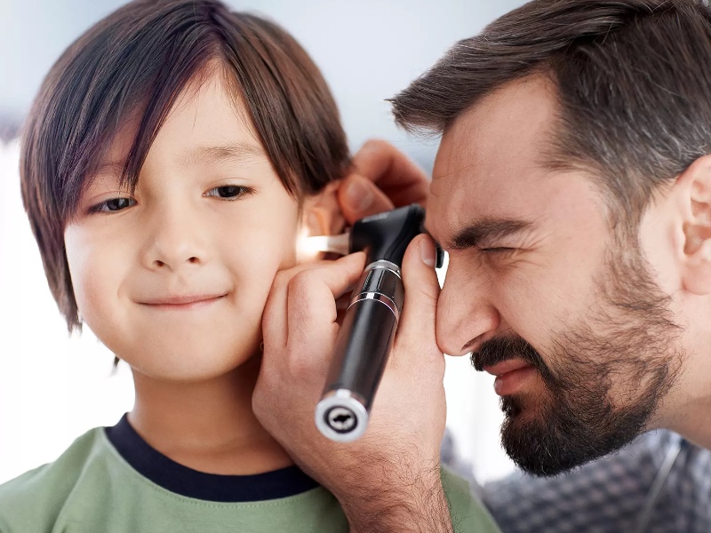 A doctor checking a paitents ear with a device.