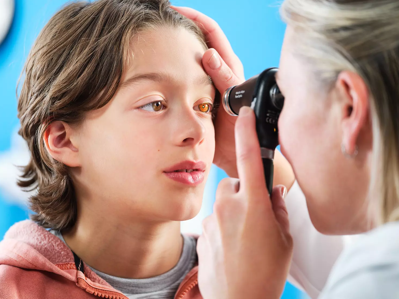 A doctor using the panoptic plus opthalmoscope on a boy.