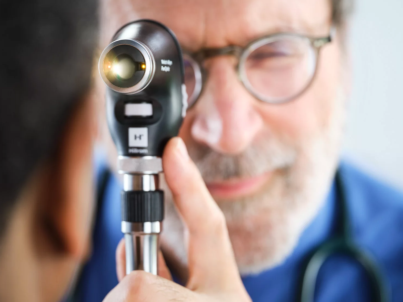 A doctor using the panoptic plus opthalmoscope on a patient.
