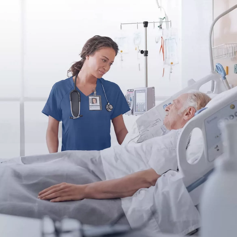 A doctor standing by a paitent in a hospital bed.
