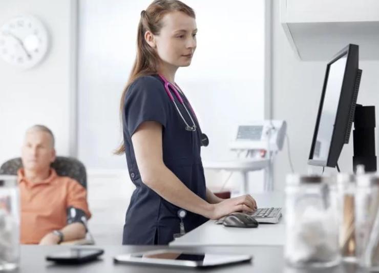 Nurse looking through records of patient data on a computer.