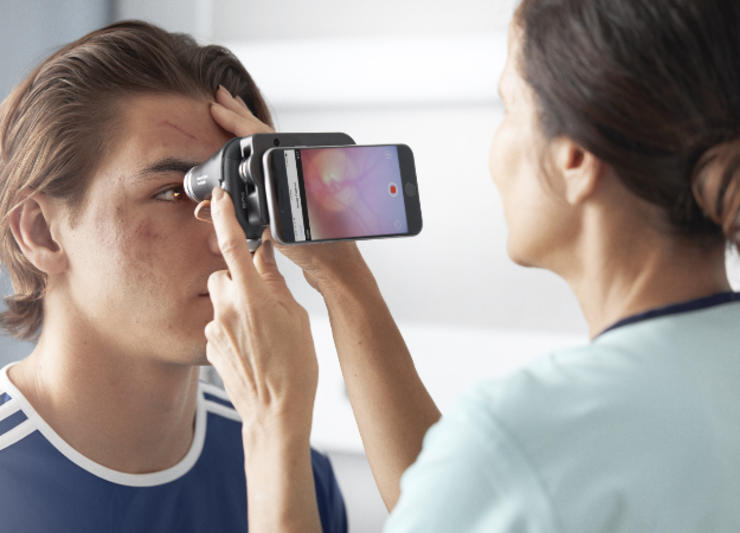 A doctor checking a patients eye using the Pan Optic.