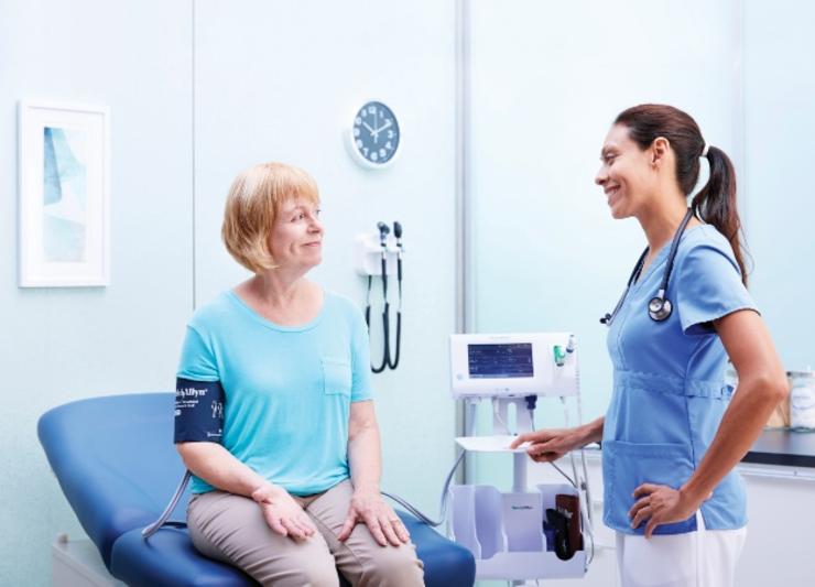 A nurse checking a patients blood pressure in a hospital room.