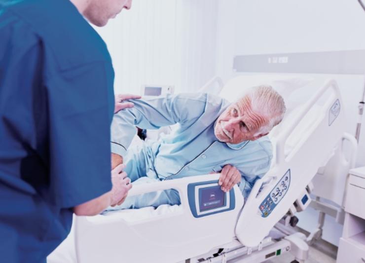 An elderly patient being helped in a Hill-rom 900 bed.